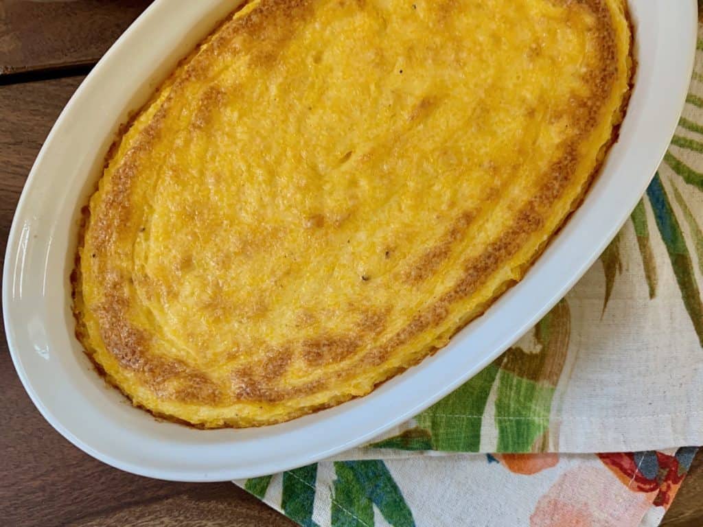 Cheese Grits Casserole baked in a white oval baking dish.
