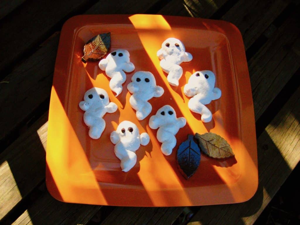 Meringue Ghost Cookies with striped shadows falling on the plate.