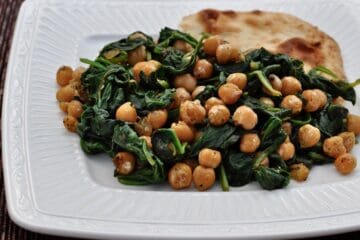 Spinach with Chickpeas served on a square plate with a piece of Tandoori Naan.