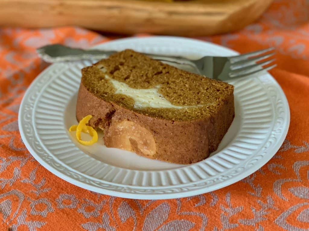 A slice of cream cheese filled Pumpkin Ribbon Bread on a small plate with a fork.