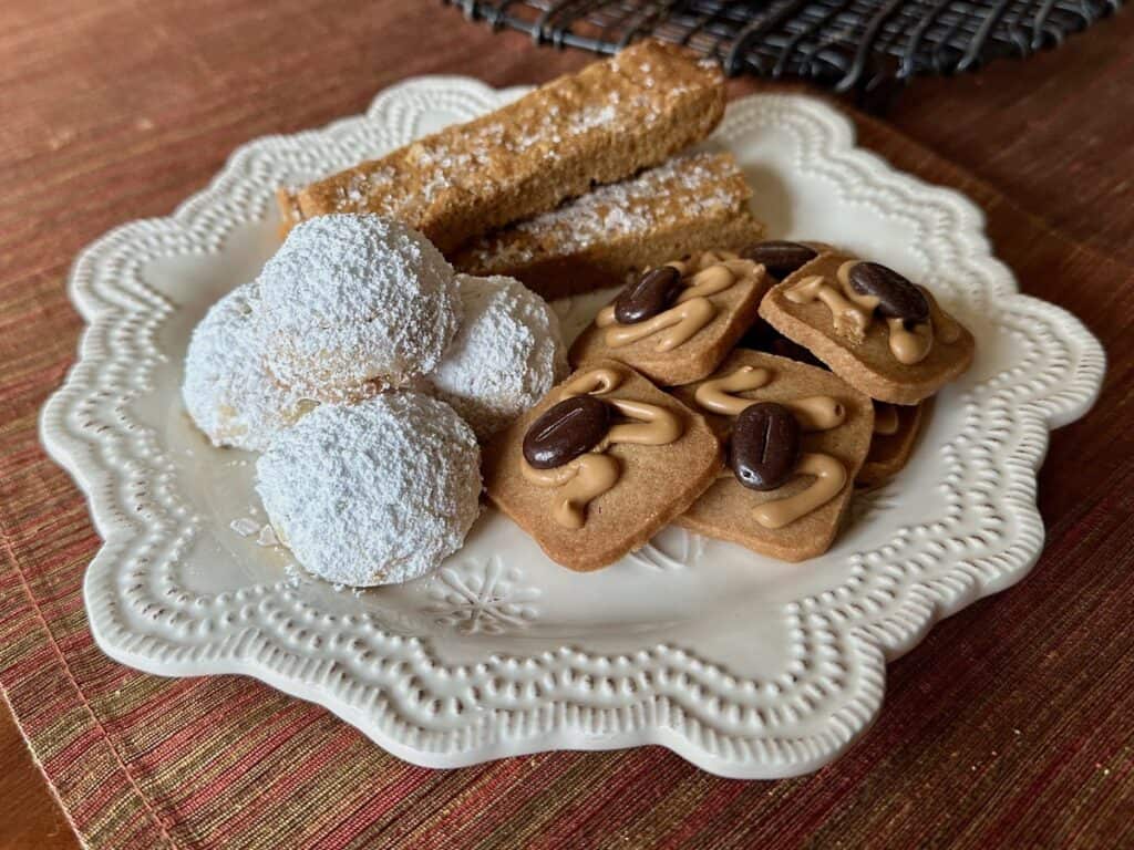 Russian Teacakes on a plate with Cinnamon Coffee Crisps and Ginger Cookie Sticks.