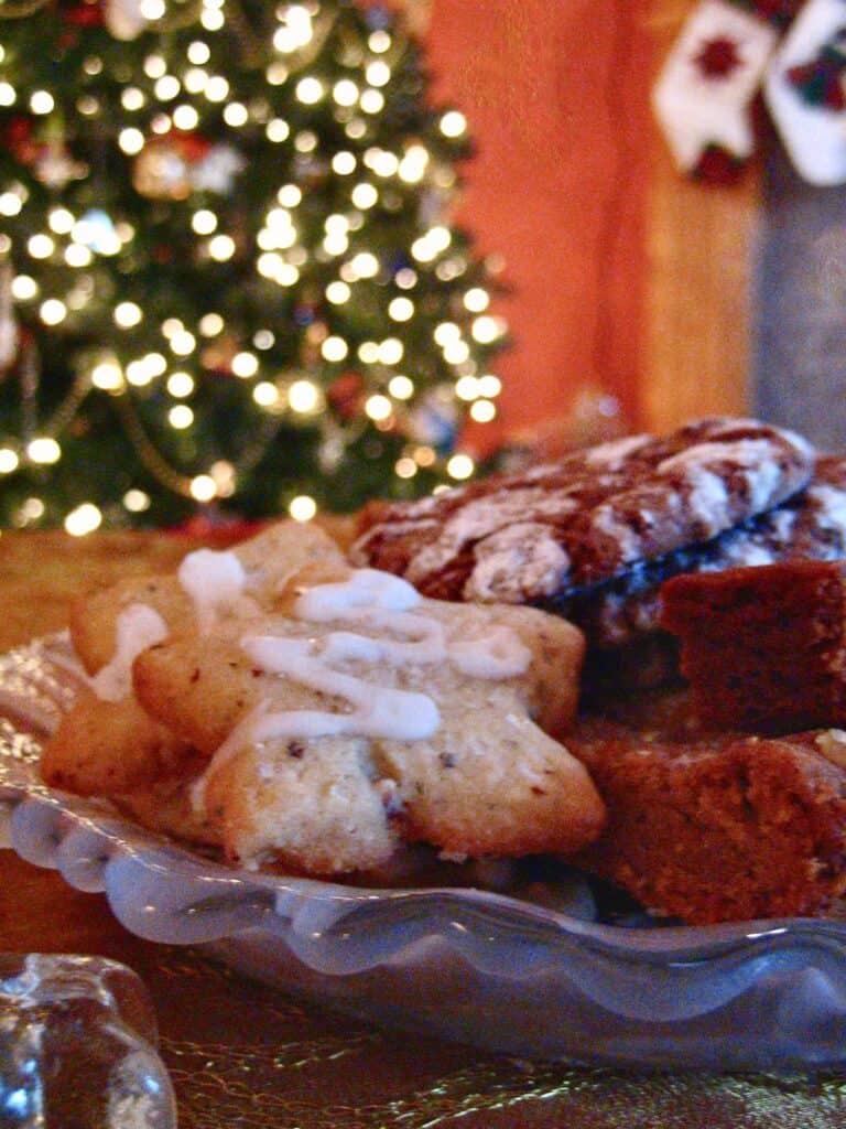 A platter of Christmas Cookies including Thyme, Hazelnut and Lemon Cookies, Chocolate Crinkles, Ginger Cookie Sticks, Russian Teacakes and Peanut Butter Fudge, served in front of the Christmas Tree. 