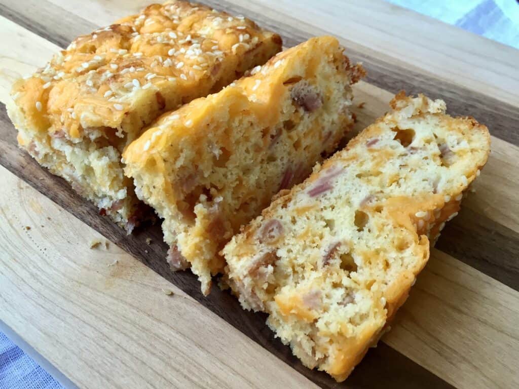 A portion of Quick Ham and Cheese Bread is sliced on a wooden cutting board.