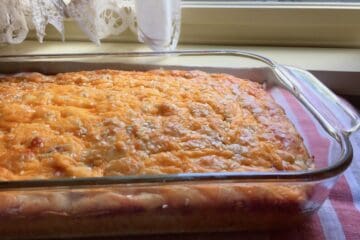 Ham and Cheese Bread, baked in a 9" x 13" pyrex casserole dish, is resting in front of a kitchen window with white curtains.