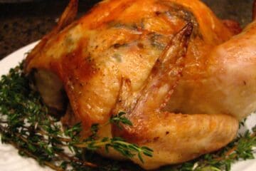 A whole Herb Roasted Chicken on a bed of thyme.