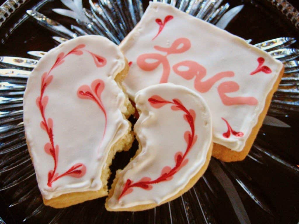Valentine Sugar Cookies with Royal Icing, one a rectangle with "Love" and heart decoration and one broken heart with a heart border.