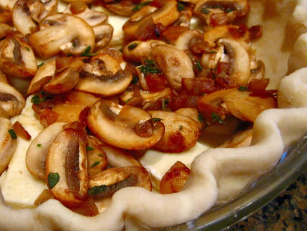 Mushrooms in the bottom of a pie pastry to make Mushroom and Brie Quiche.