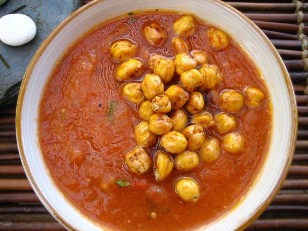 A bowl of freshly made Gazpacho topped with Saffron Roasted Chickpeas in a ceramic bowl.