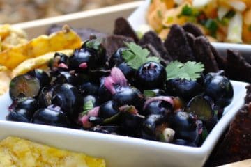 Blueberry Salsa in a square white bowl served with Tortilla chips in a wooden tray