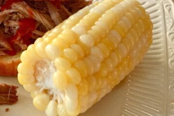 Corn on the Cob served beside a barbecue sandwich.