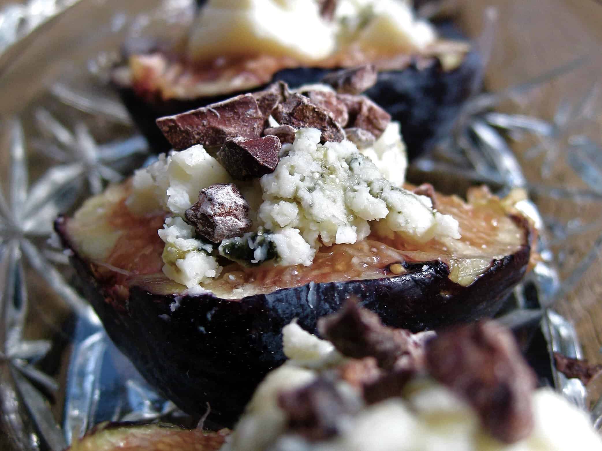 Figs stuffed with Blue Cheese and Cacao Nibs served on a glass tray.