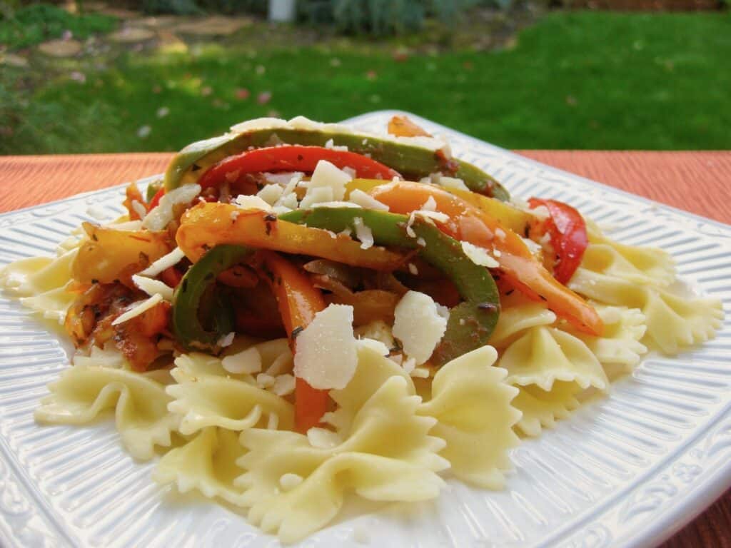 Four Pepper Pasta topped with shredded parmesan on a white plate.