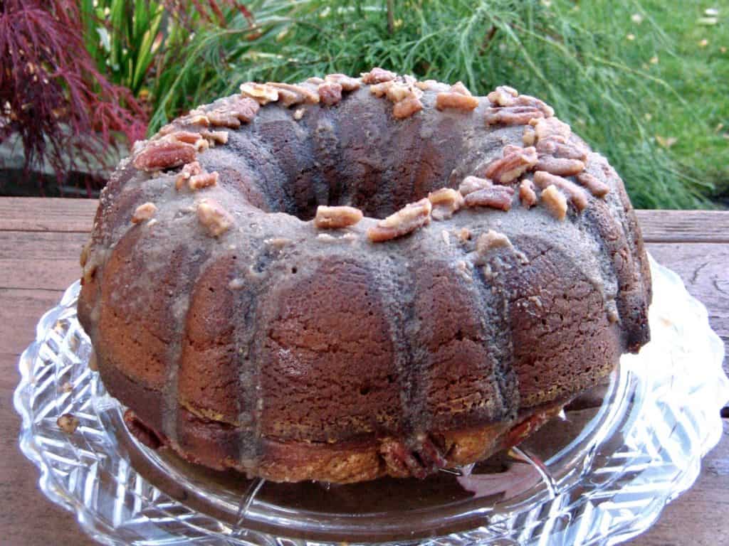 Pumpkin Praline Cake topped with Praline Glaze on a glass plate in the garden.