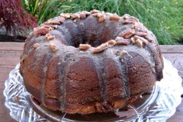 Pumpkin Praline Cake topped with Praline Glaze on a glass plate in the garden.