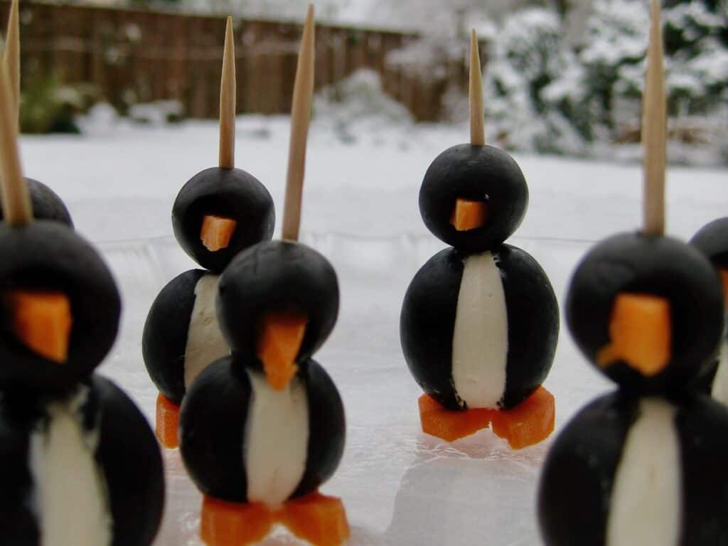Olive Penguins arranged on a glass plate in the snow.