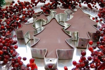 Peanut Butter Fudge Cutouts topped with chocolate on a pewter dish surrounded by a red berry garland.