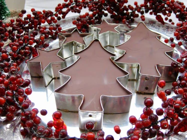 Peanut Butter Fudge Cutouts topped with chocolate on a pewter dish surrounded by a red berry garland.