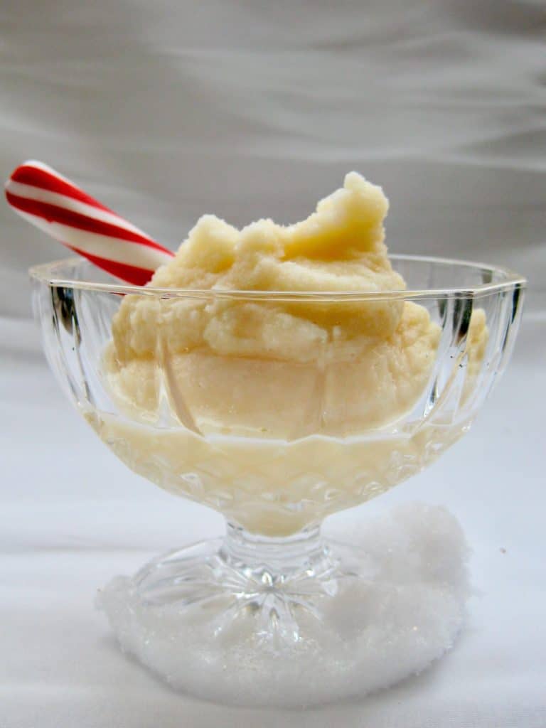 Snow Cream in a glass dessert dish garnished with a peppermint stick.