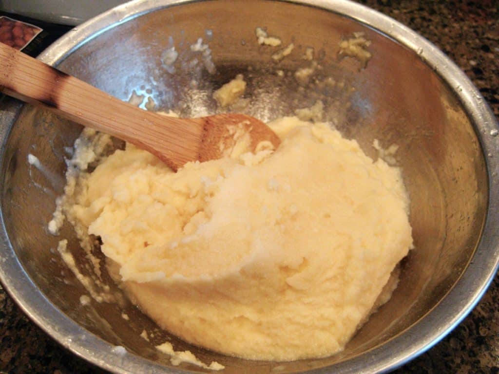 Snow Cream in a metal mixing bowl stirred with a wooden spoon.