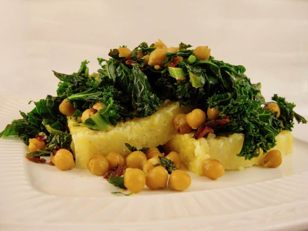 Kale with Sun-dried Tomatoes and Garbanzo Beans is served over thick slices of Italian Polenta.