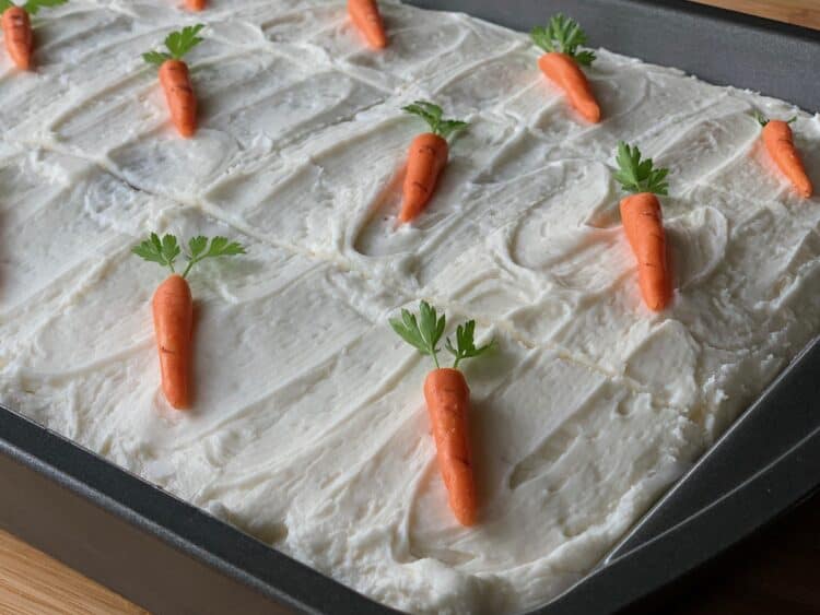 Carrot Cake baked in a 9 x 13-inch pan and topped with cream cheese frosting and cream cheese carrots.