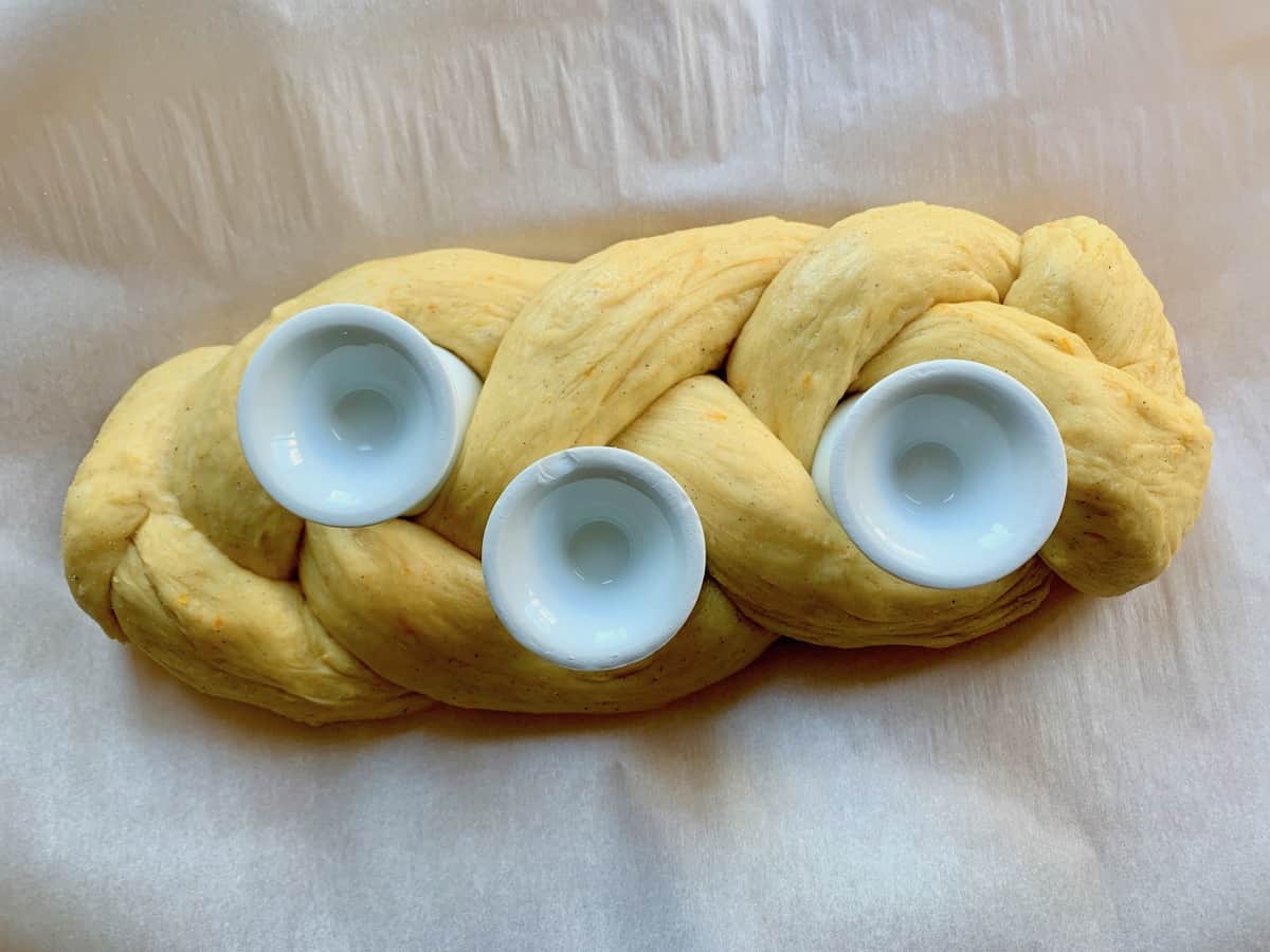 Upside down egg cups tucked into a Cardamom Citrus Easter Braid to make space for colored Easter eggs.
