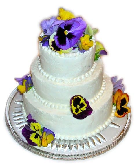 A three tiered 25th anniversary cake decorated with fresh pansies.