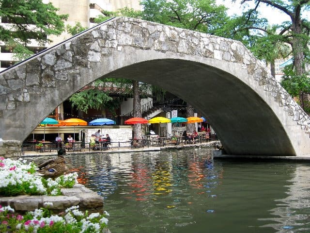 Colorful awnings are reflected in the water along the Riverwalk in San Antonio near the bridge to Casa Rio.