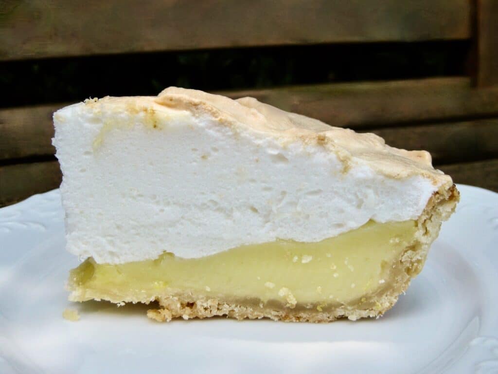 A slice of Lemon Meringue Pie on a white plate.