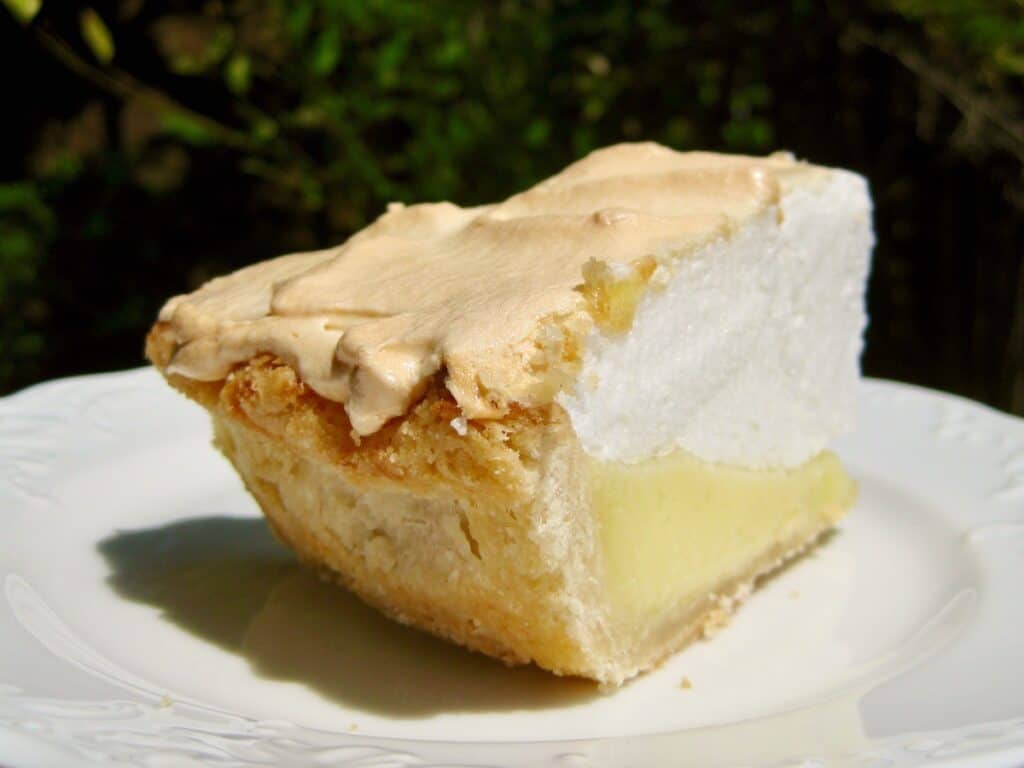 A slice of Lemon Meringue Pie, topped with No Weep Meringue, served on a white dessert plate.