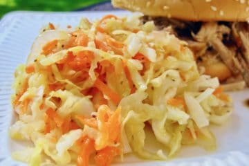 Railroad Cole Slaw served beside a Pulled Pork Sandwich on a white plate.