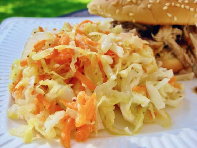 Railroad Cole Slaw served beside a Pulled Pork Sandwich on a white plate.