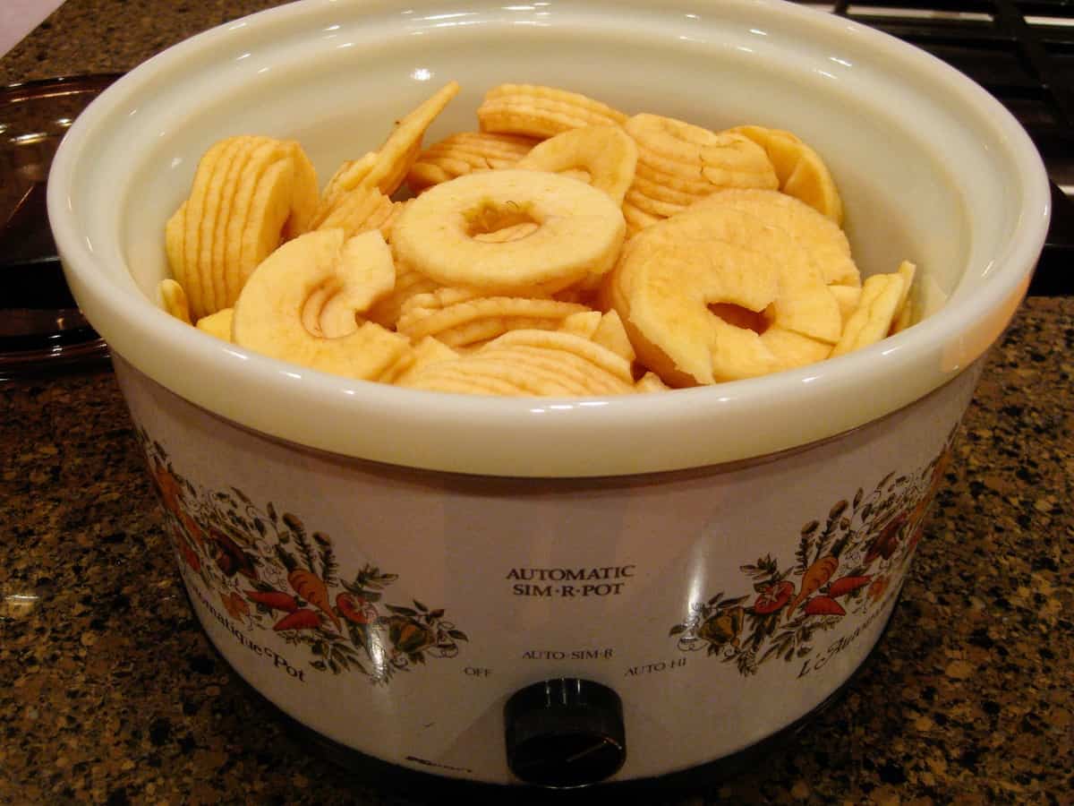 The bowl of a slow cooker filled with sliced apples to make Homemade Apple Butter.