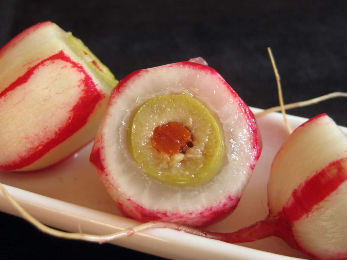Trimmed Cocktail Eyeball with radish root on a ceramic olive tray. 