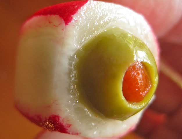 Hollowed radish filled with pimiento stuffed olive to form a Cocktail Eyeball.