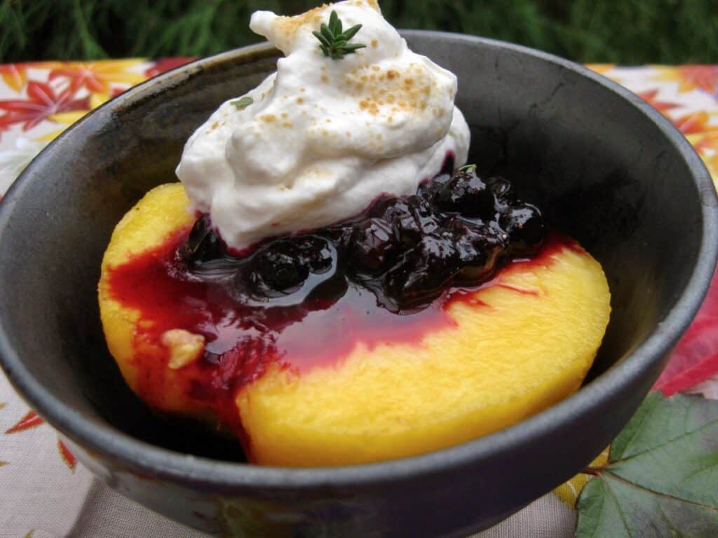 A fresh ripe peach half topped with Huckleberry Thyme Sauce and a big dollop of sweetened whipped cream. 