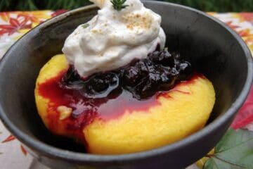 A fresh ripe peach half topped with Huckleberry Thyme Sauce and a big dollop of sweetened whipped cream.