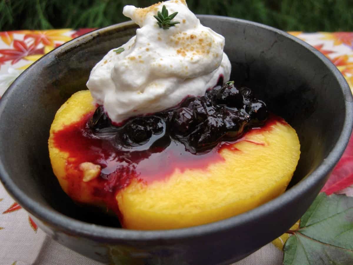 A fresh ripe peach half topped with Huckleberry Thyme Sauce and a big dollop of sweetened whipped cream.