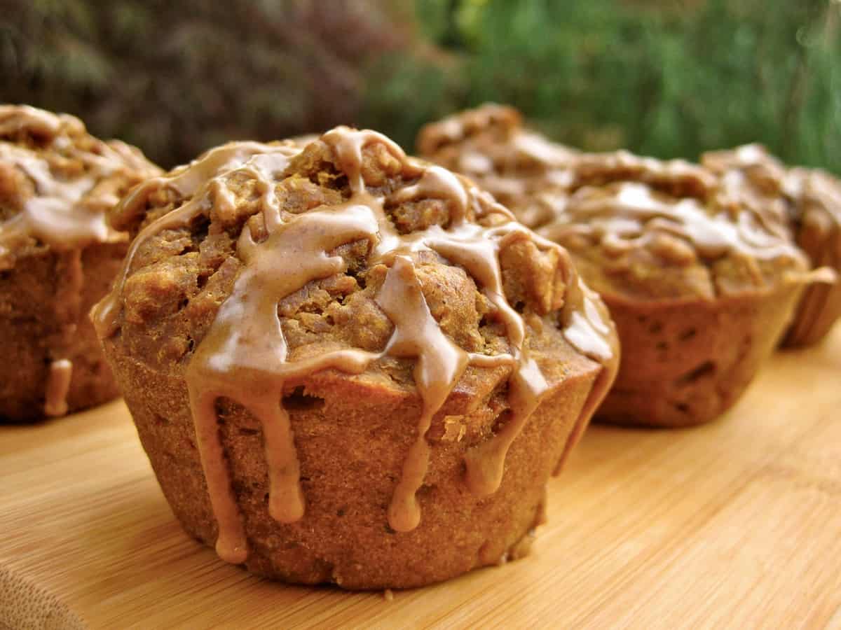 A Pumpkin Spice Latte Muffin drizzled with a Pumpkin Coffee Glaze dripping down the sides.