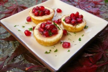 Pomegranate Goat Cheese Tarts on a square plate surrounded by autumn leaves.