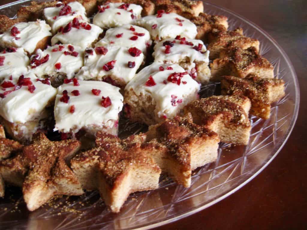 Cranberry Pecan Bars with Orange Cream Cheese Frosting displayed on a tray with Snickerdoodle Blondies cut into stars. 