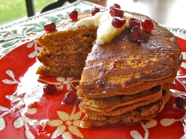 Gingerbread Pancakes topped with pomegranate arils on a red and white plate