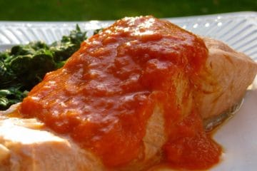 Pan Simmered Salmon topped with Roasted Red Pepper Sauce served on a white plate.