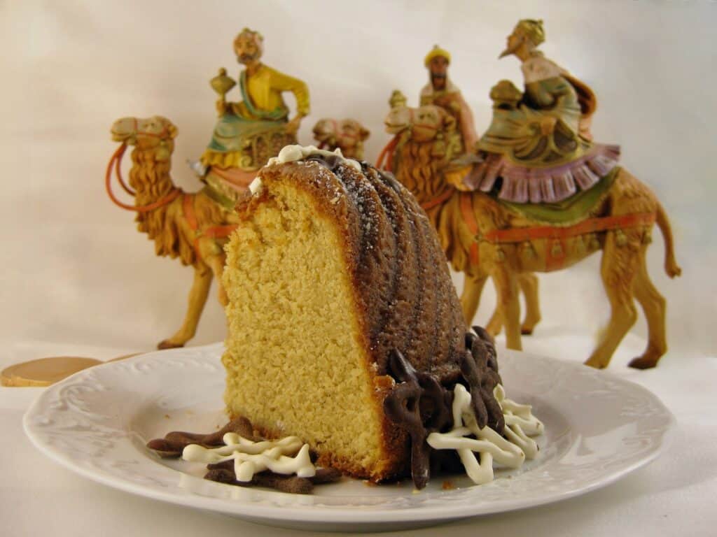 A Slice of Eggnog Pound Cake decorated with chocolate stars as a Twelfth Night Cake with figures of the Three Wise Men on camels in the background.