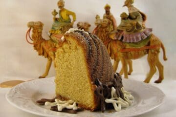 A Slice of Eggnog Pound Cake decorated with chocolate stars as a Twelfth Night Cake with figures of the Three Wise Men on camels in the background.