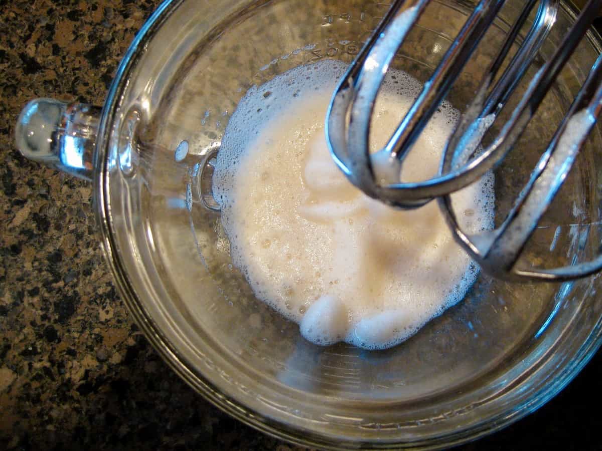 Eggwhites in a glass mixing bowl, beaten until foamy.