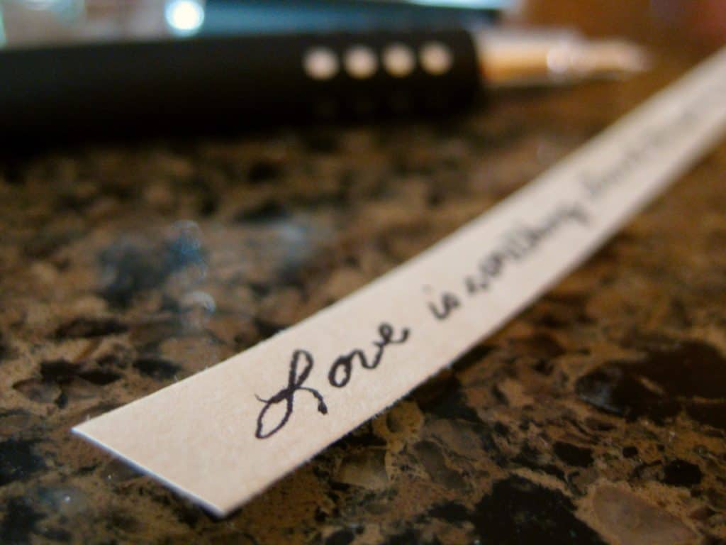 A handwritten expression of love is prepared to fill a homemade Fortune Cookie.