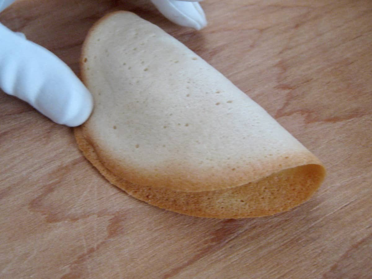 Fold Homemade Fortune Cookies quickly using a pair of white gloves or close fitting oven mitts.