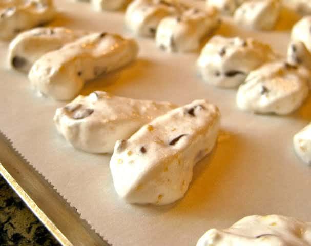 Heart shaped Meringue Cookies are piped onto a parchment-lined baking sheet, ready to bake.
