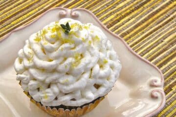 A Lemon Olive Oil Cupcake frosted with a swirl of Balsamic Whipped Cream, sprinkled with lemon zest and garnished with a sprig of lemon thyme.